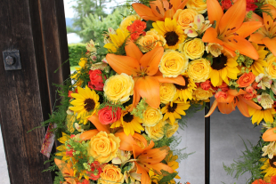 Ausschnitt von einem Trauerkranz in Gelb orange mit Rosen, Lilien und Sonnenblumen